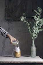 person pouring milk on glass mason jar