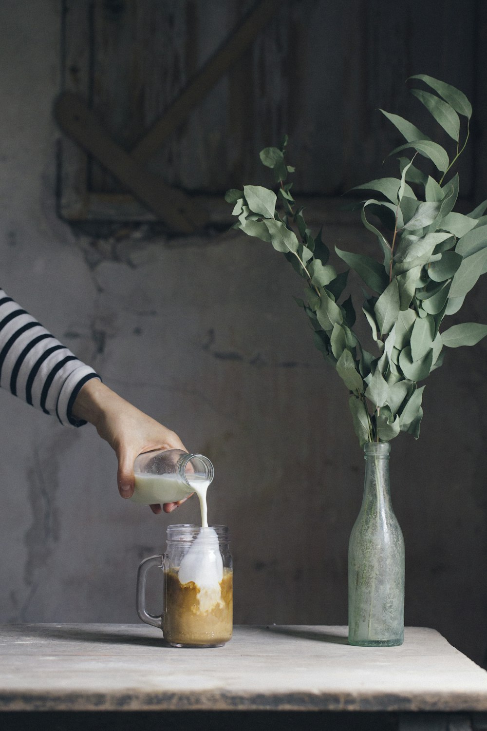 person pouring milk on glass mason jar