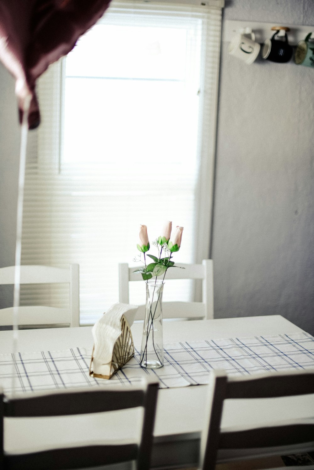 Jarrón de vidrio transparente con flores sobre mesa de comedor de madera