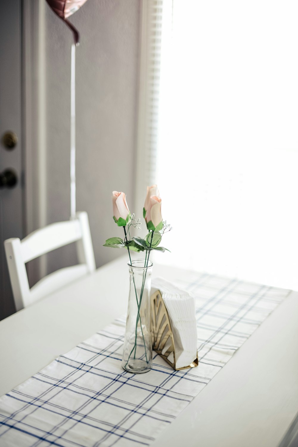 rosas rosas en jarrón de vidrio en mesa de comedor