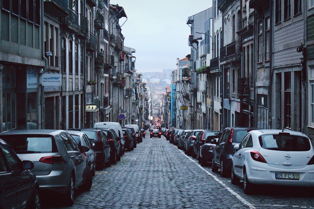 vehicles parked at sidewalk between buildings