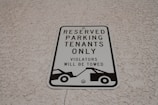 A parking sign attached to a textured wall, indicating reserved parking for tenants only. It warns that violators will be towed and features a graphic of a tow truck.