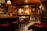 Cozy bar interior with seven seats and a warmly lit counter in dark gray and gold tones.