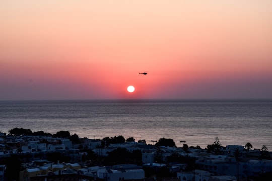 helicopter flying on sky near town and body of water in Santorini Greece
