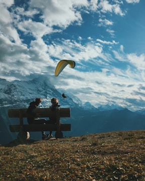 two person sitting on bench under white and blue clouds