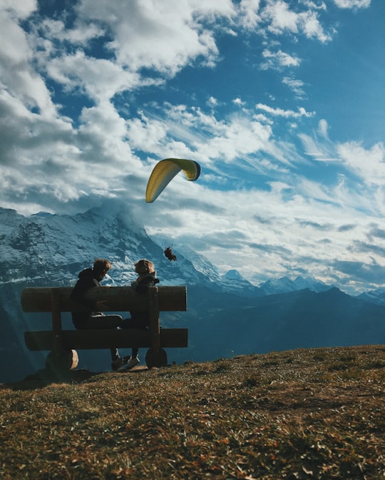 two person sitting on bench under white and blue clouds in First Switzerland