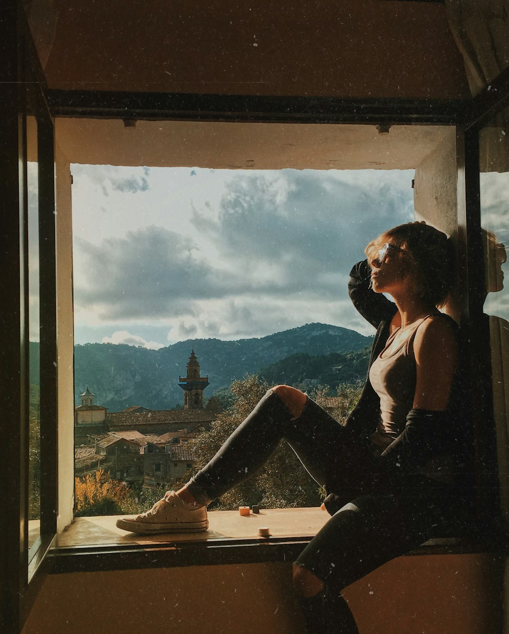 a woman sitting on a window sill looking out the window