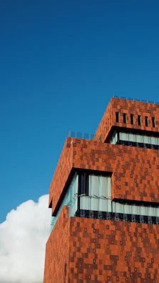 A modern terrestrial laser scanner capturing colorful point cloud data of a commercial building exterior.