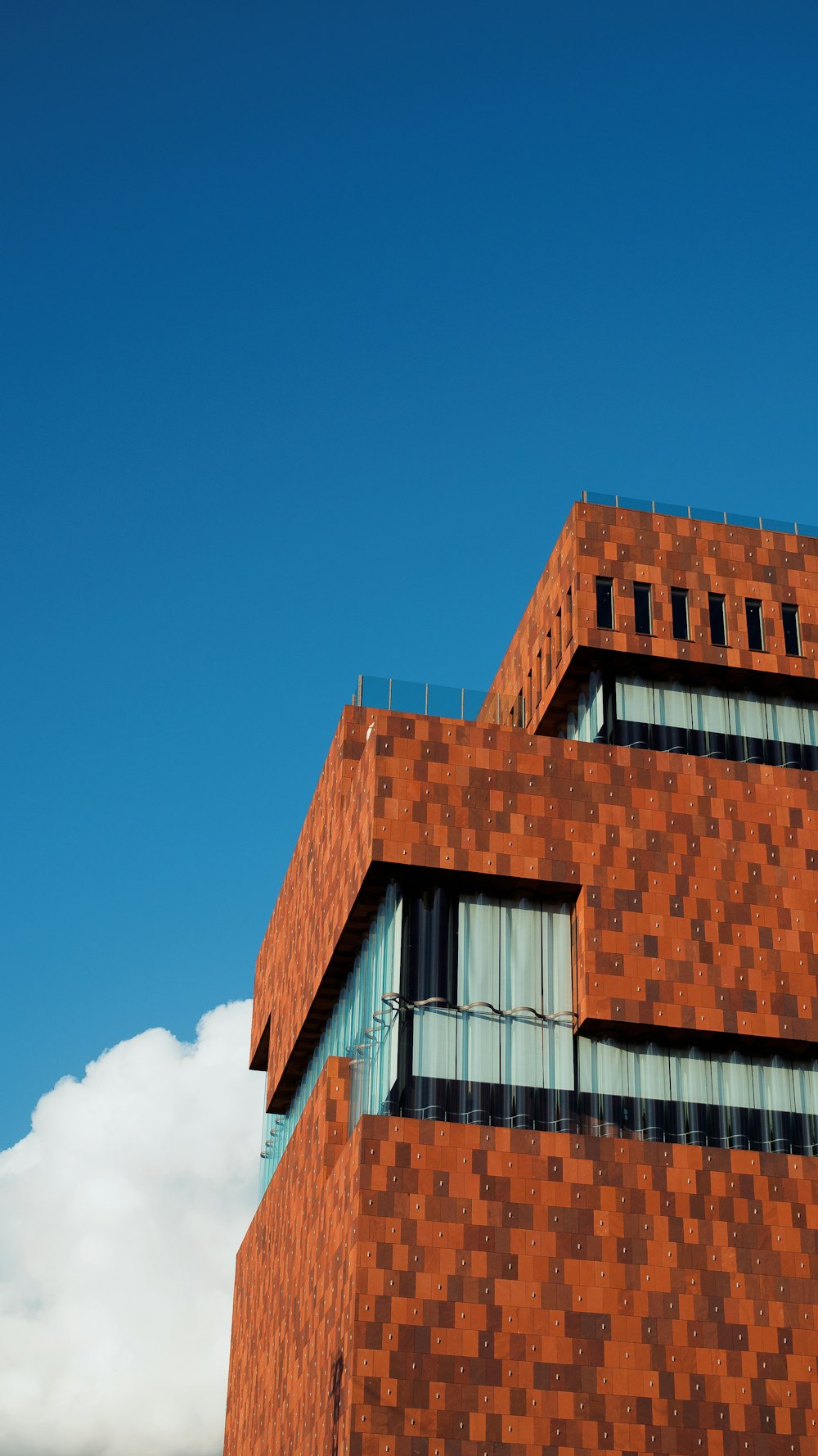 Fotografía de ángulo bajo de un edificio marrón y gris bajo el cielo azul y blanco