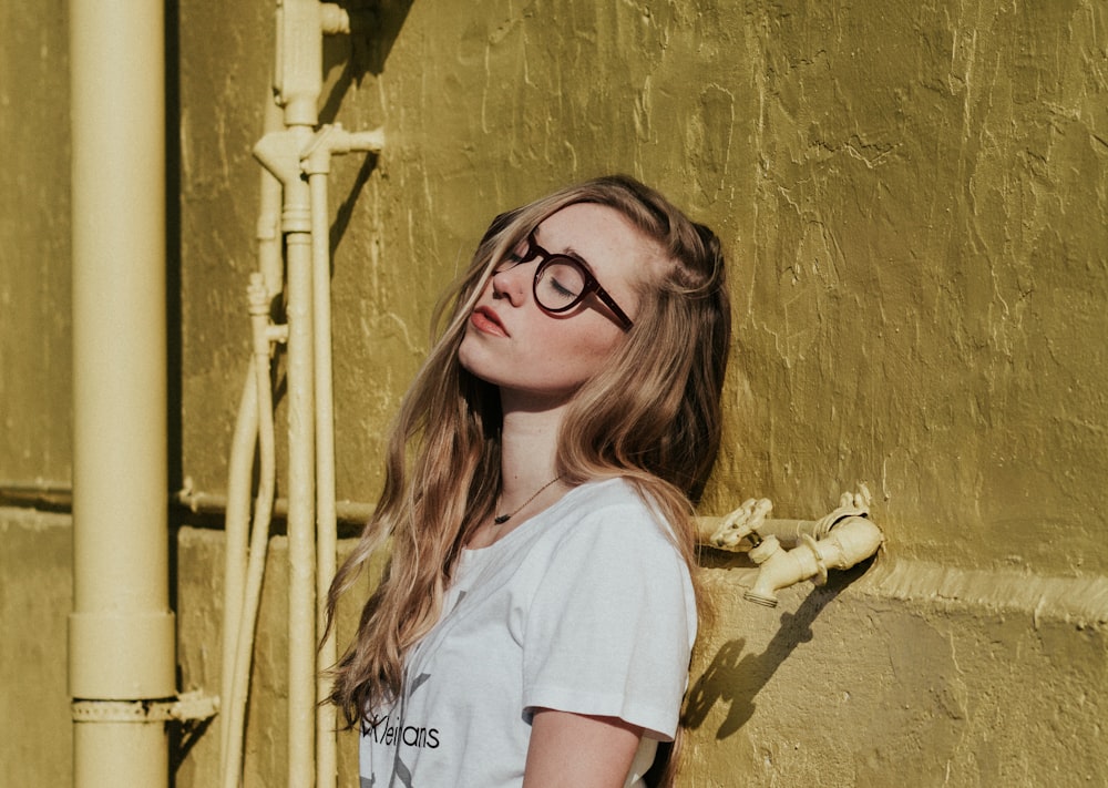 woman leaning on brown wall beside spigot