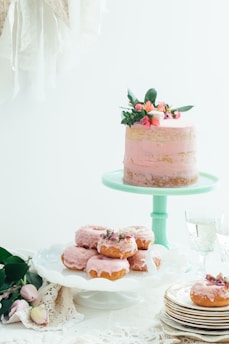 A pastel delicately decorated with pastel blue and pink frosting, sitting on a rustic wooden table.