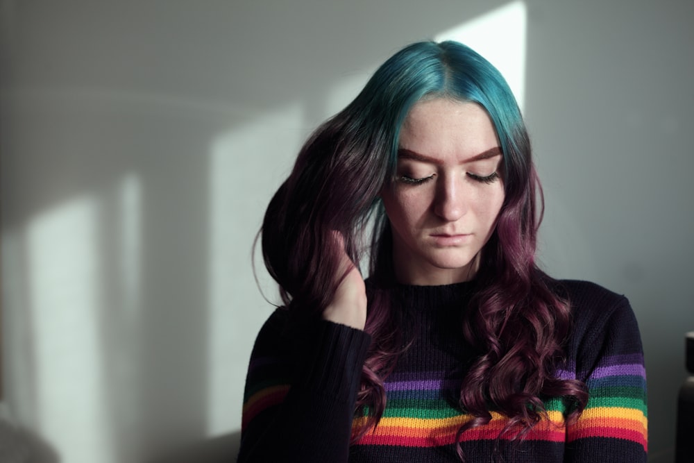 mujer sosteniendo su cabello en la sala de pintura de la pared blanca