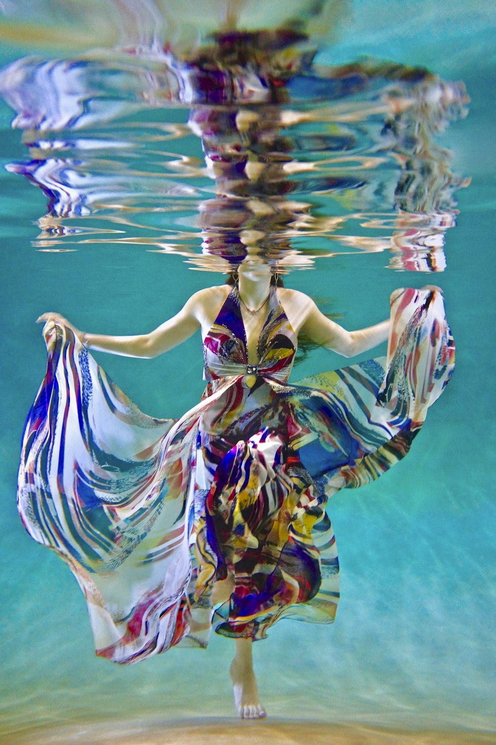 underwater photography of woman in dress swimming