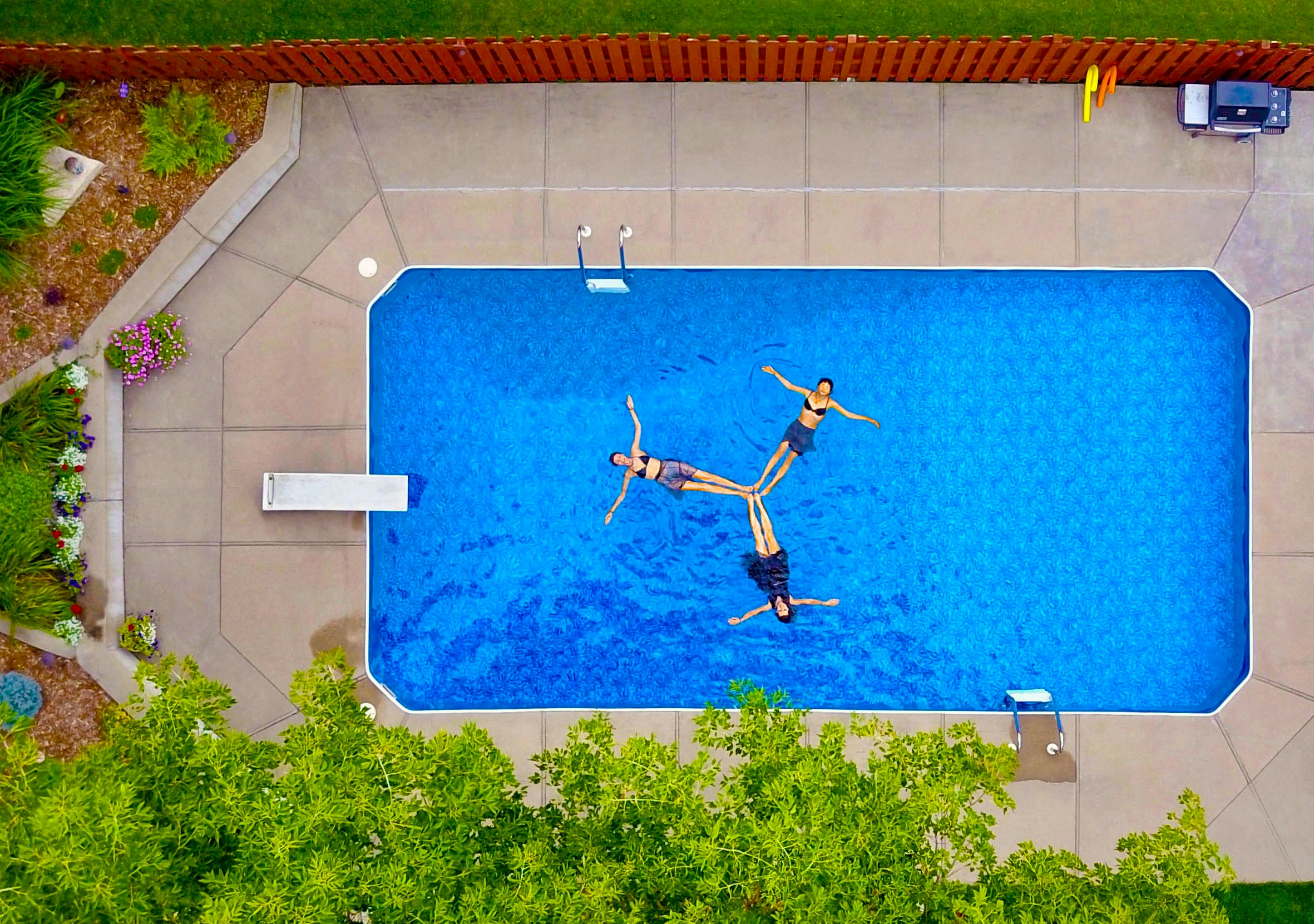 aerial photography of three women floating on pool forming propeller