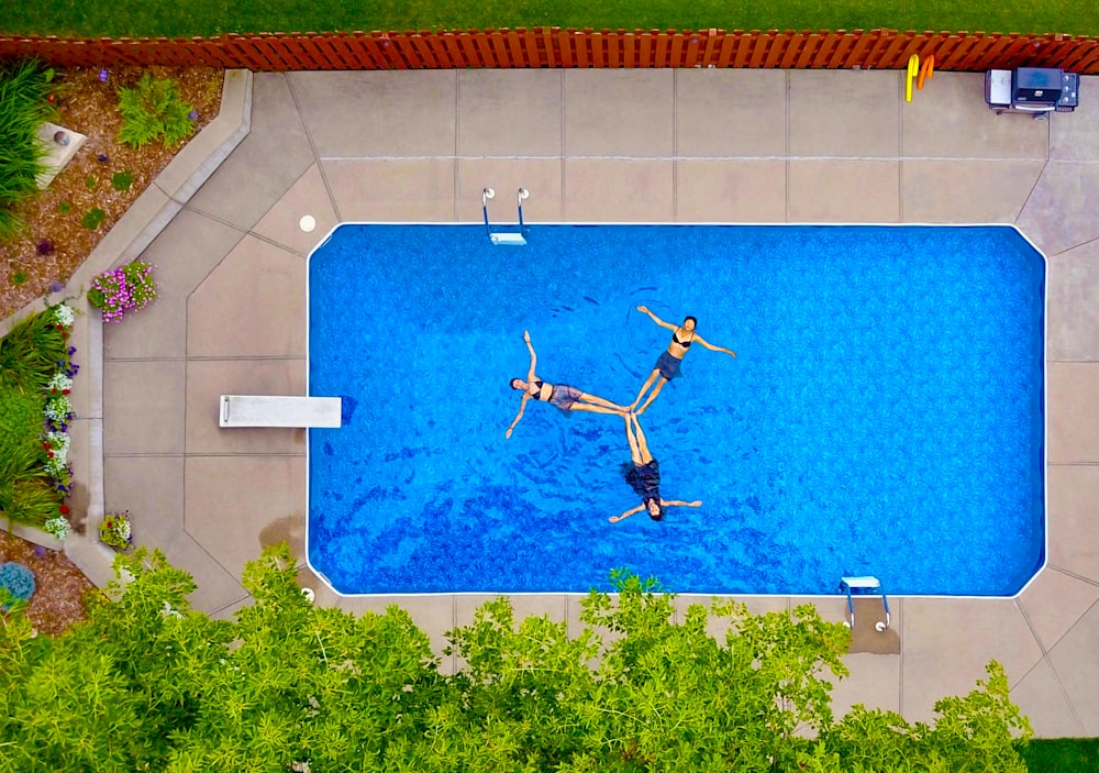 aerial photography of three women floating on pool forming propeller
