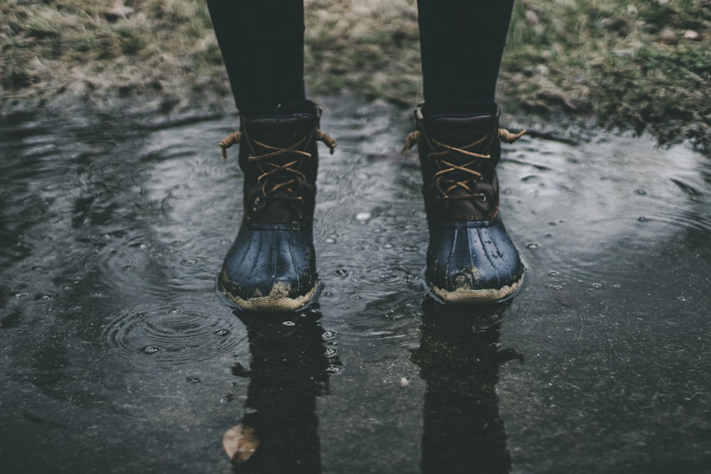 person wearing black boots standing on water
