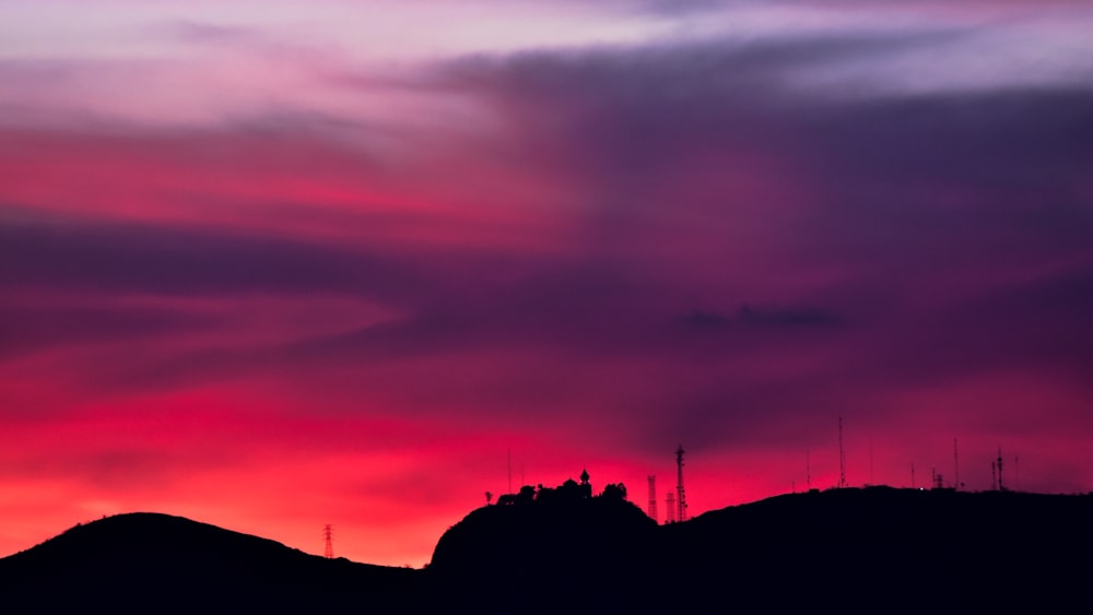 silhouette on rock under purple and pink skies