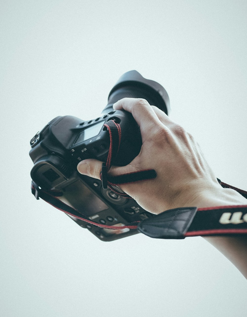 person holding camera with camera lens and camera lens hood