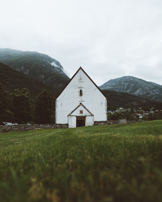 white concrete church near mountain peaks in Hardangerfjord Norway