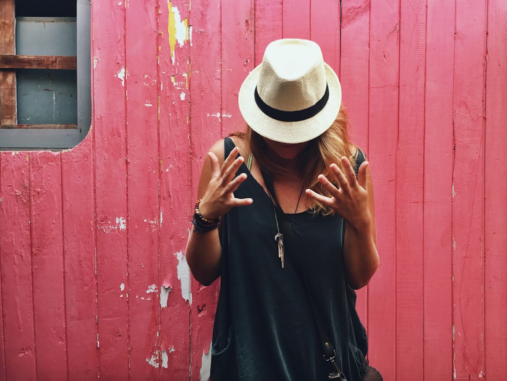 woman wearing white sun hat beside red wall