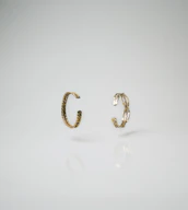 Minimalist display of golden rings and bracelets on a smooth beige surface with subtle shadows.