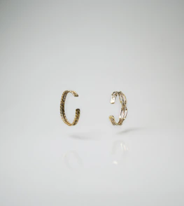 Minimalist display of golden rings and bracelets on a smooth beige surface with subtle shadows.
