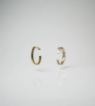 Rows of gleaming 18k gold plated brass rings lined up on a minimalist cream surface.