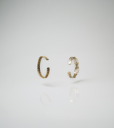 Stacked gold-plated rings catching the light against a smooth marble background.