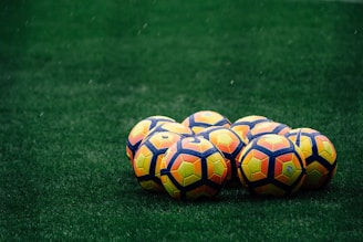 pile of yellow-orange-and-red Nike soccer balls