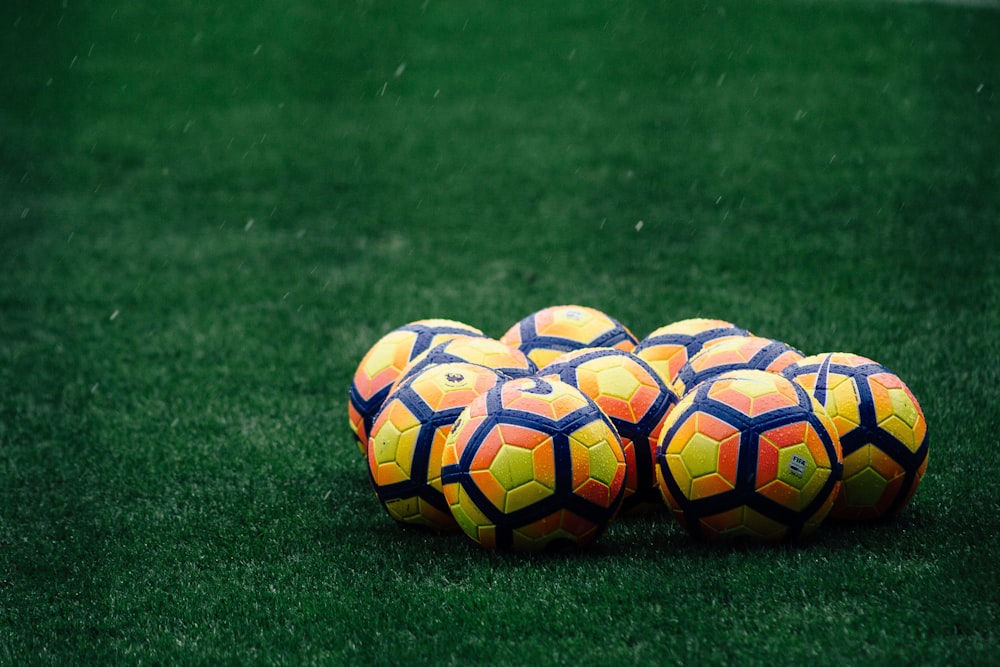 pile of yellow-orange-and-red Nike soccer balls