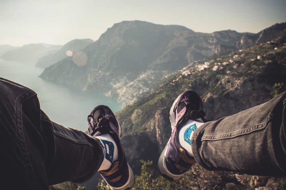 person sitting on cliff over body of water during daytime