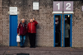 a couple of men standing next to a brick building