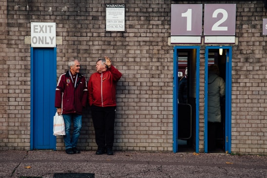 a couple of men standing next to a brick building