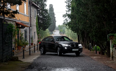 black sedan parking on road near green trees