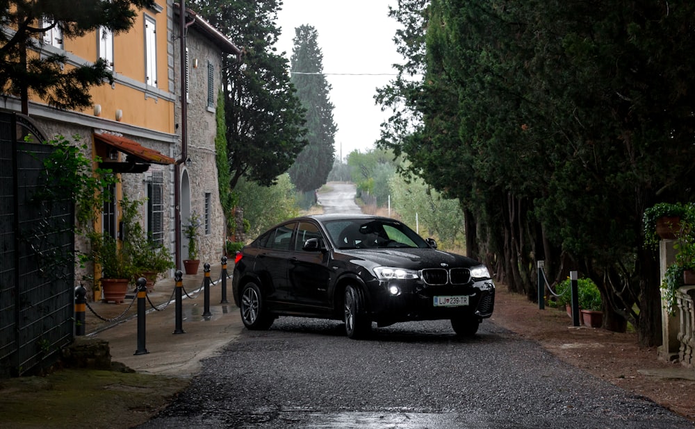 Estacionamiento de sedán negro en la carretera cerca de árboles verdes