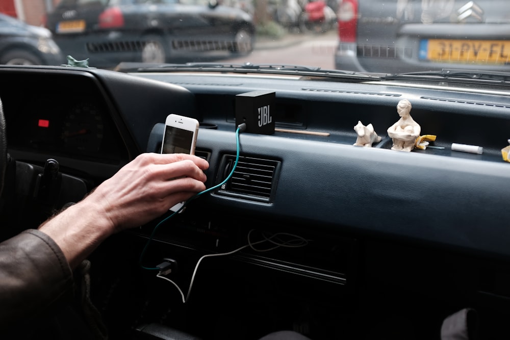 person hand holding iPhone 6 on dashboard during daytime