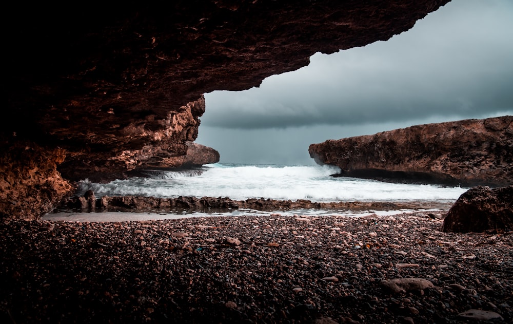 shore under rock formation during cloudy day