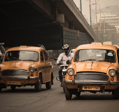 person riding motorcycle in between of two yellow taxi vehicle