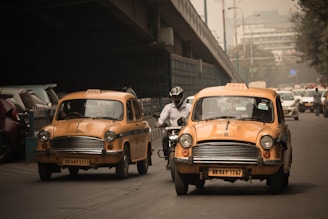 person riding motorcycle in between of two yellow taxi vehicle