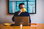 man drinking coffee in front of the laptop computer
