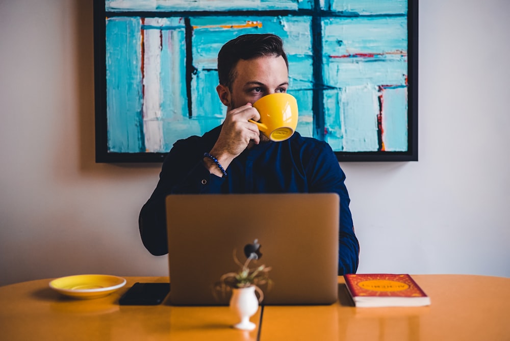 man drinking coffee in front of the laptop computer