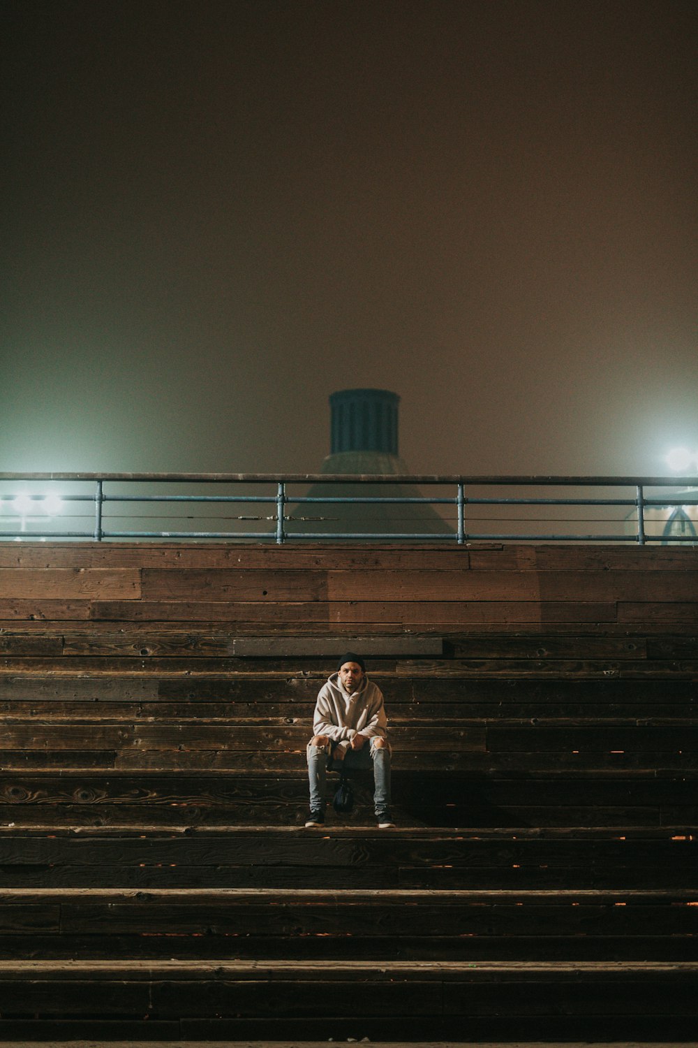 man sitting on bleachers during nighttime