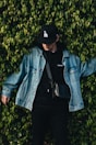man in denim jacket beside bush