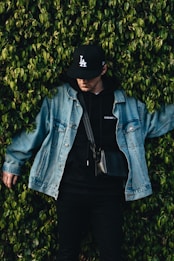 man in denim jacket beside bush