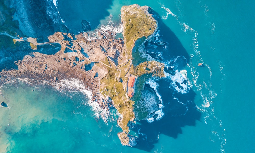 Foto aus der Vogelperspektive von Meereswellen, die an Felsbrocken zermalmen