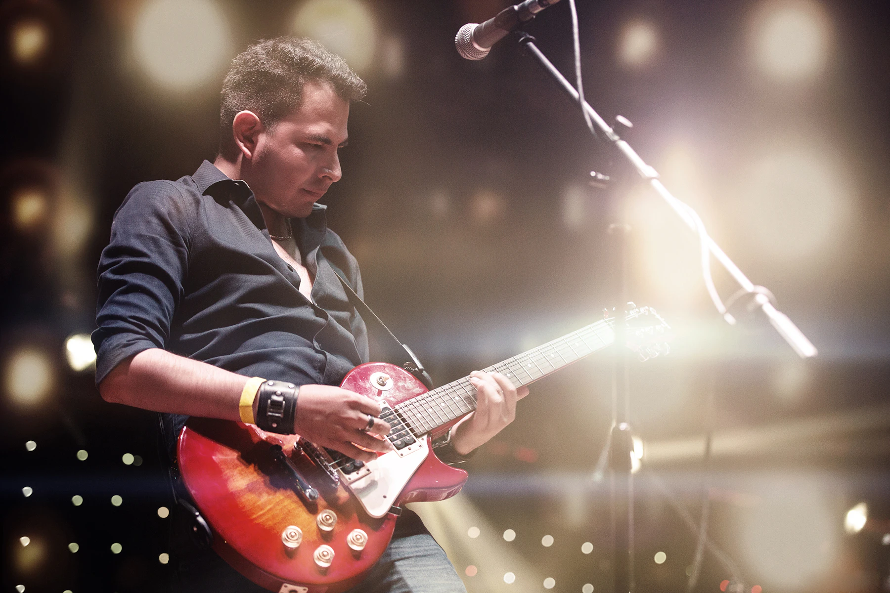 A musician playing an electric guitar under stage light
