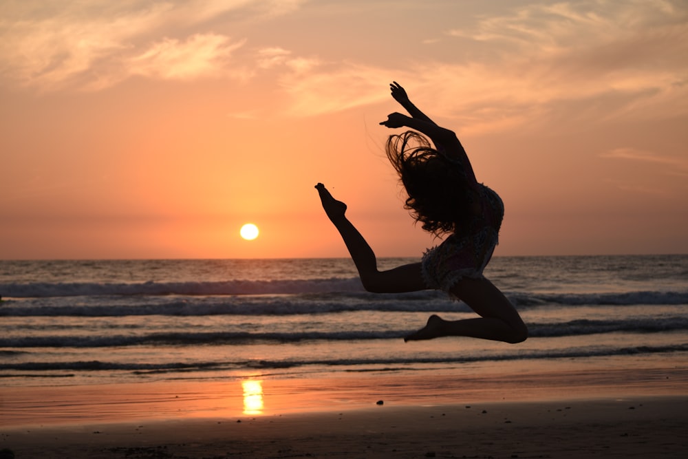 Silhouette einer Frau, die während der goldenen Stunde springt