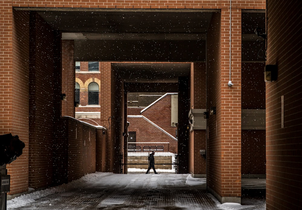 silhouette of person walking on brown concrete building at daytime