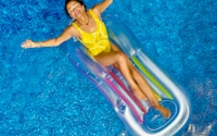 woman riding on plastic floating buoy on body of water