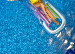 woman riding on plastic floating buoy on body of water